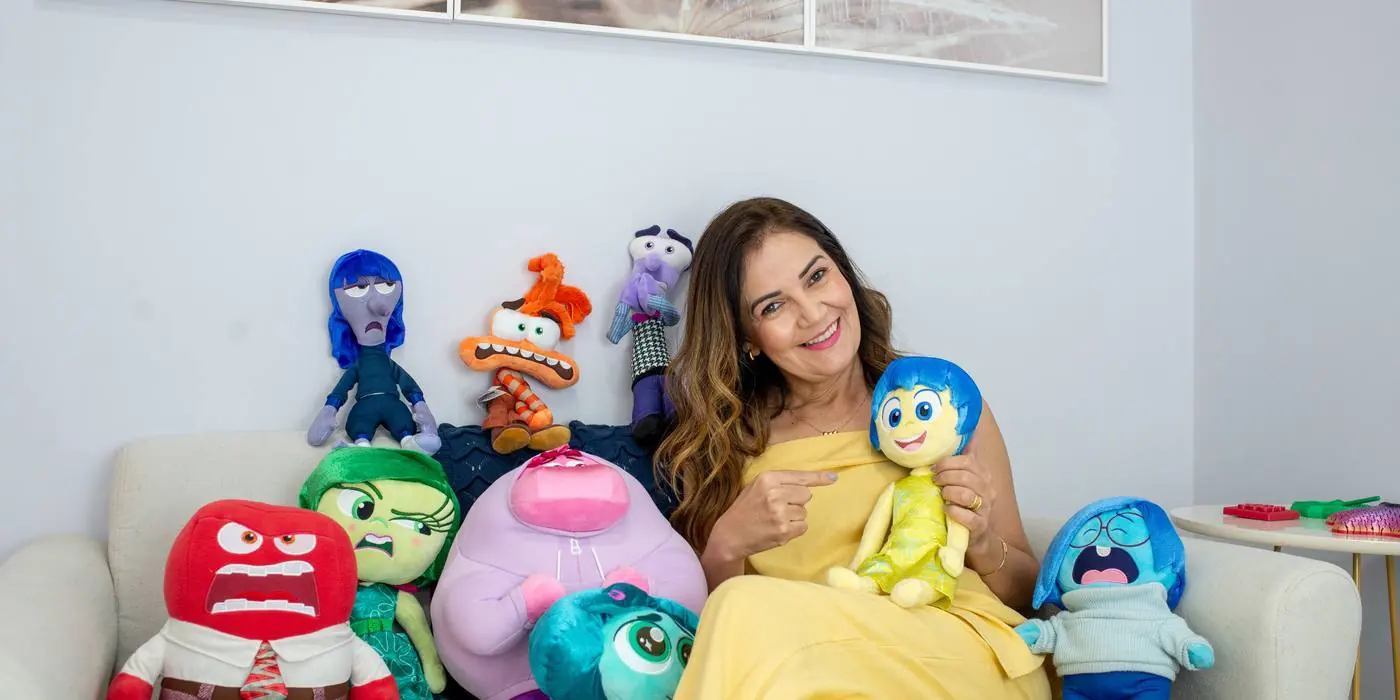 Gracielle sentada no consultório com os bonecos que representam as emoções, usados no trabalho com crianças